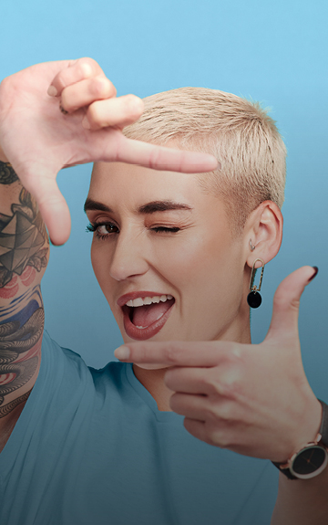 Eine junge Frau mit blonden kurzen Haaren formt mit ihren Fingern ein Viereck.